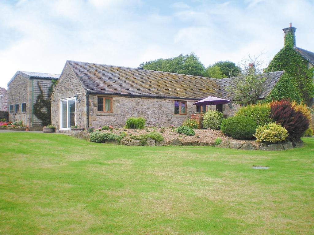 een stenen huis met een tuin ervoor bij Meadowside Cottage in Calton