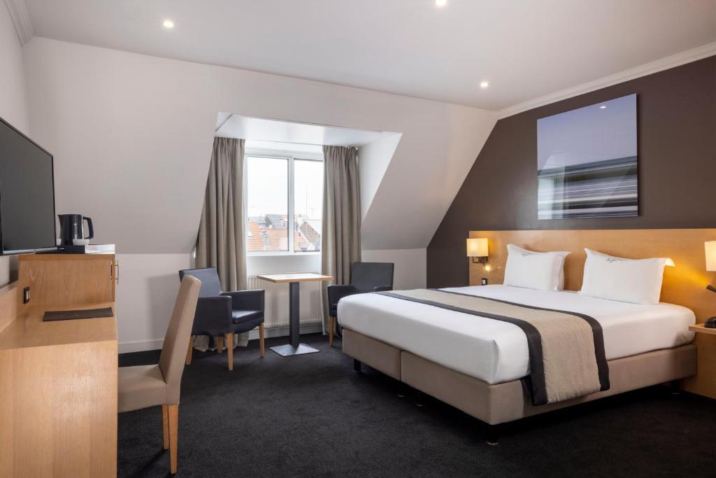 a hotel room with a bed and a desk and a tv at Hotel The Augustin in Brussels