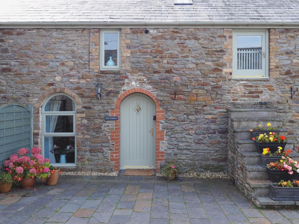 a brick house with a white door and flowers at The Granary in Dunvant