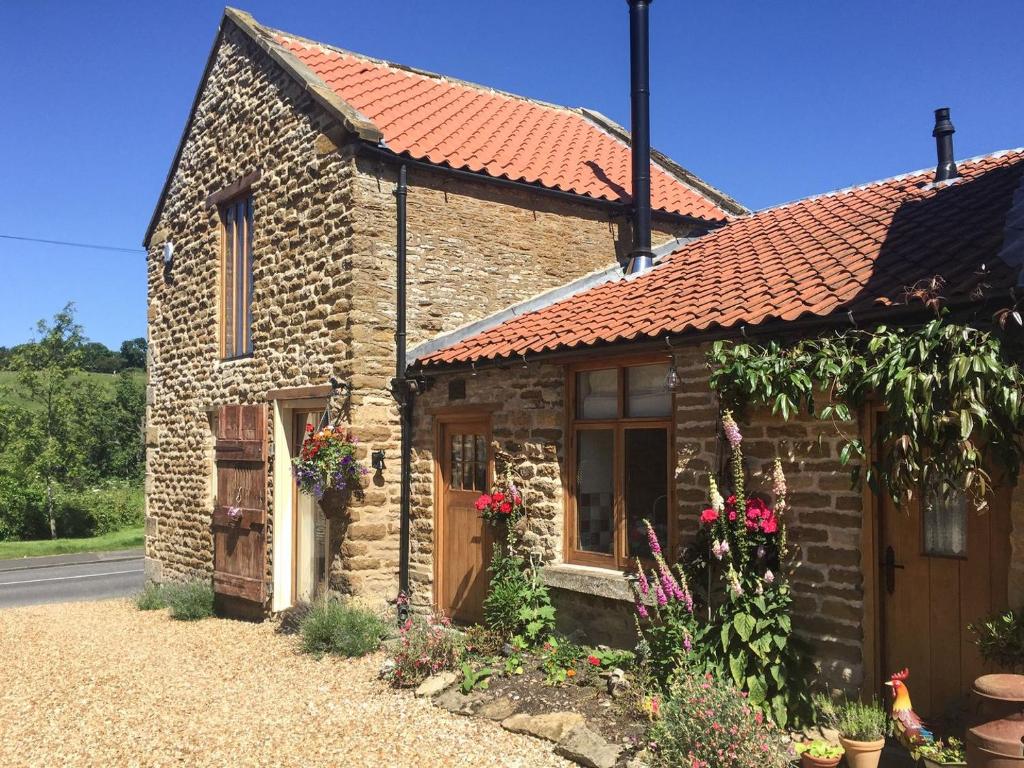 uma pequena casa de pedra com um telhado vermelho em Manor House Dairy Cottage em Ayton