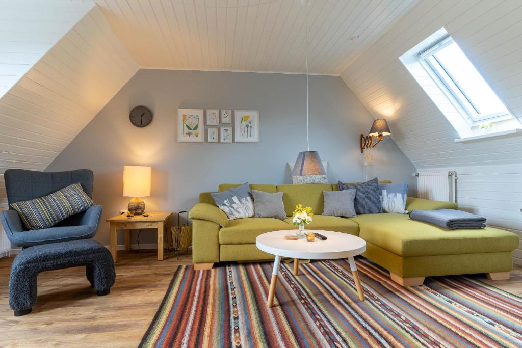 a living room with a green couch and a chair at Ferienwohnung-Elli in Garding