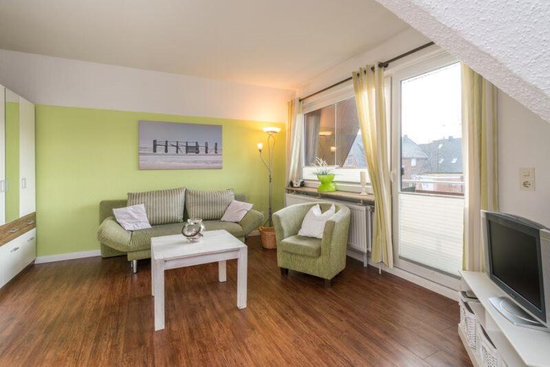 ein Wohnzimmer mit einem Sofa, einem Tisch und einem TV in der Unterkunft Haus Angela - Appartement Tom in Sankt Peter-Ording