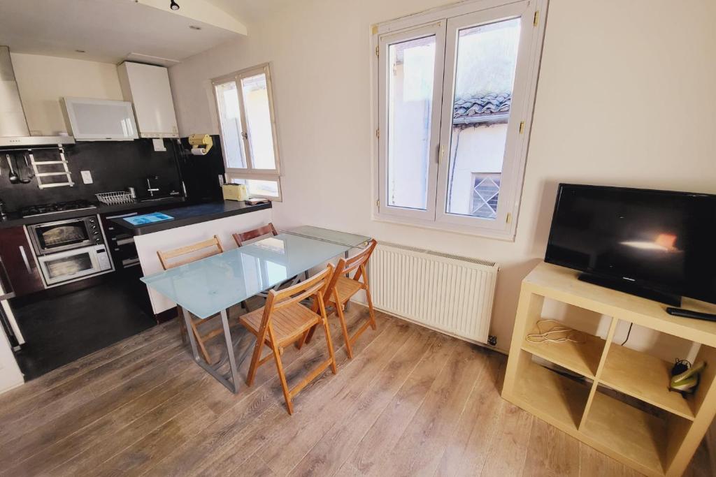 ein Wohnzimmer mit einem Glastisch und eine Küche in der Unterkunft Comfortable studio in the historical center in Avignon