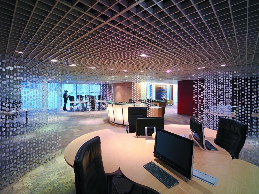 A contemporary hotel lobby with communal computer workstations and a curved reception desk.