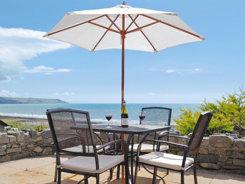 a table with an umbrella and two glasses of wine at Morlais - Hw7599 in Llanaber