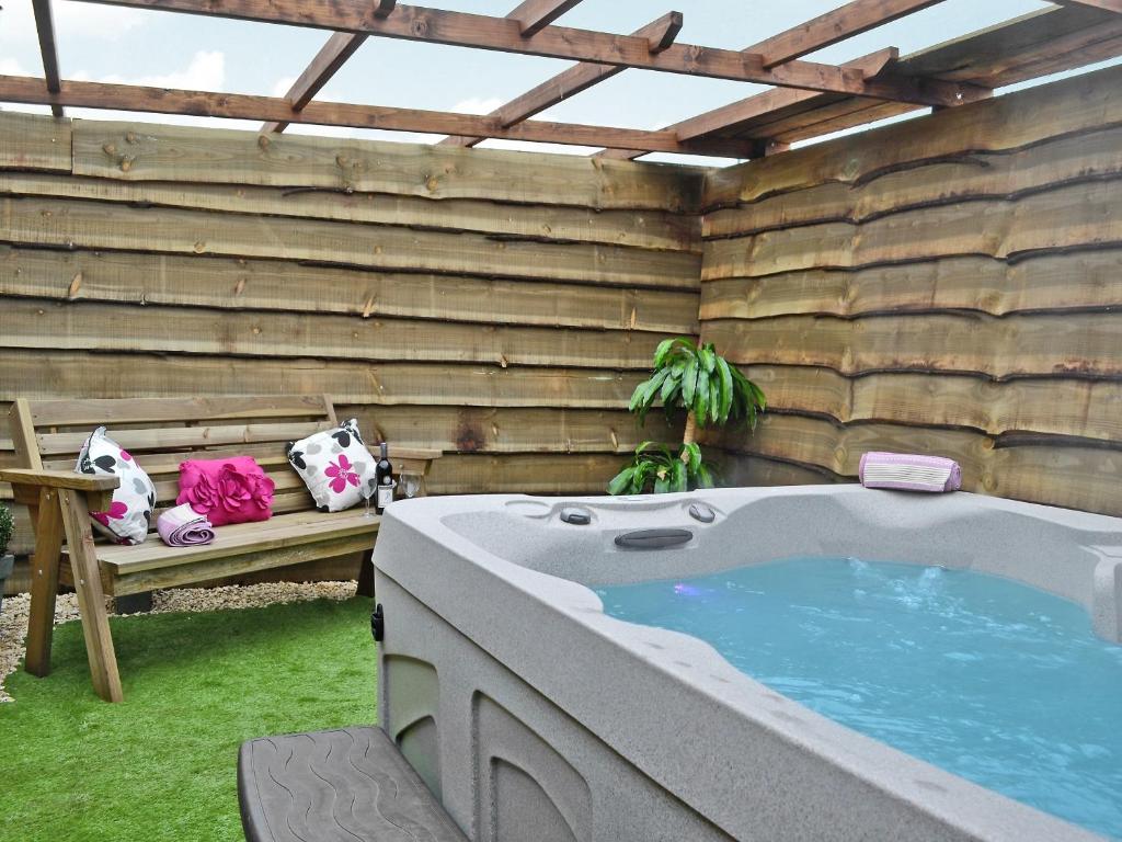 a jacuzzi tub in a backyard with a bench at The Stables in Bream