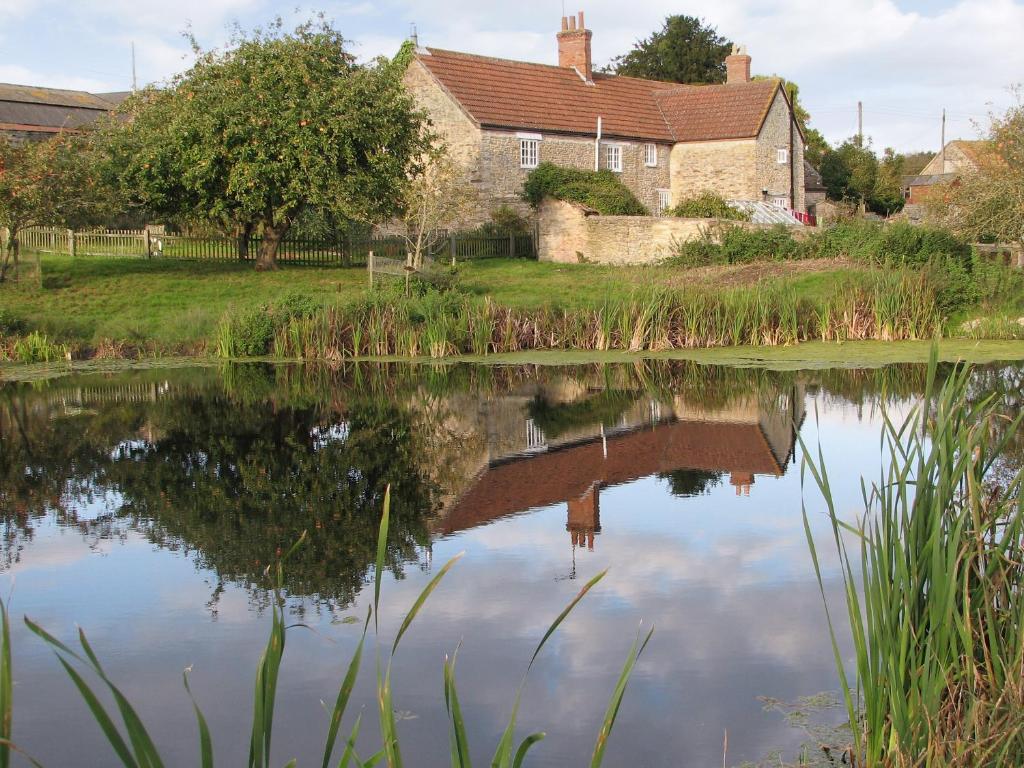 a house reflected in the water of a lake at Old Orchard Cottage in Haydon