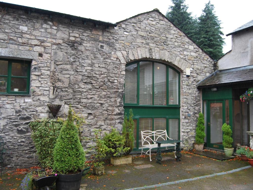 una casa de piedra con un banco delante en The Old Woodyard, en Kendal