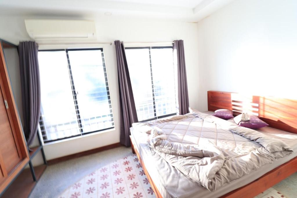 a bedroom with a bed and two large windows at Theary apartment in Phumi Ta Phul