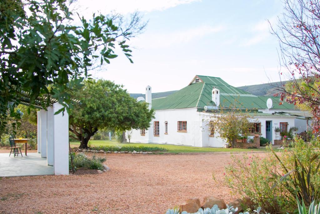 a large white house with a green roof at Blue Cow Barn - Boutique Farm in Barrydale