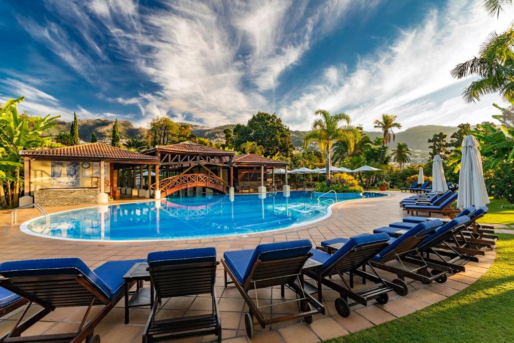 a swimming pool with blue chairs and a group at Quinta Jardins do Lago in Funchal