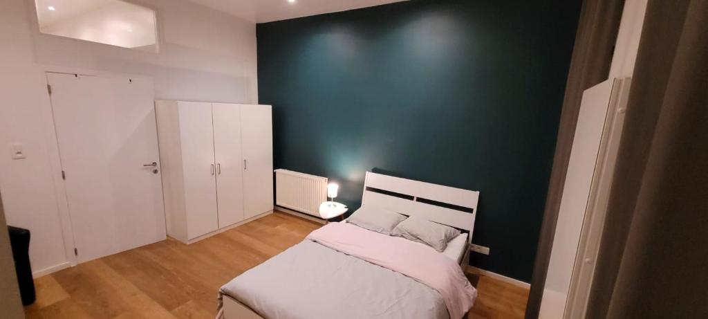 ein Schlafzimmer mit einem Bett und einer grünen Wand in der Unterkunft Bruxelles ma belge in Brüssel