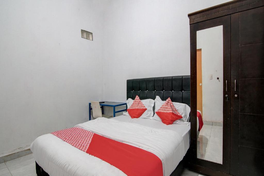 a bedroom with a bed with red and white pillows at OYO 92111 Dinda Homestay Syariah in Dumai