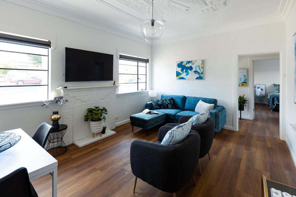 a living room with a blue couch and a tv at Art deco inner city comfort in Bendigo