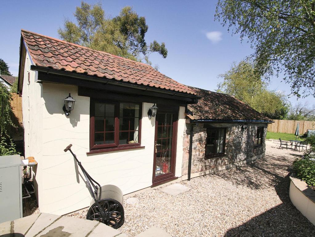 a small cottage with a wheelbarrow in front of it at Quantock Hideaway in Nether Stowey