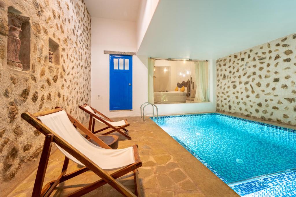 a swimming pool in a room with two chairs next to it at Conch Resort Luxury Private Pool Suites in Puducherry