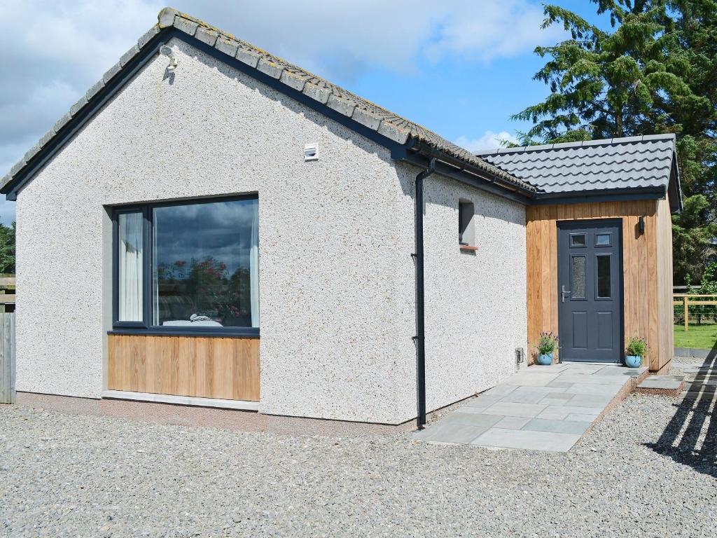 um pequeno edifício branco com uma janela e uma porta em Barn Owl Cottage em Inver