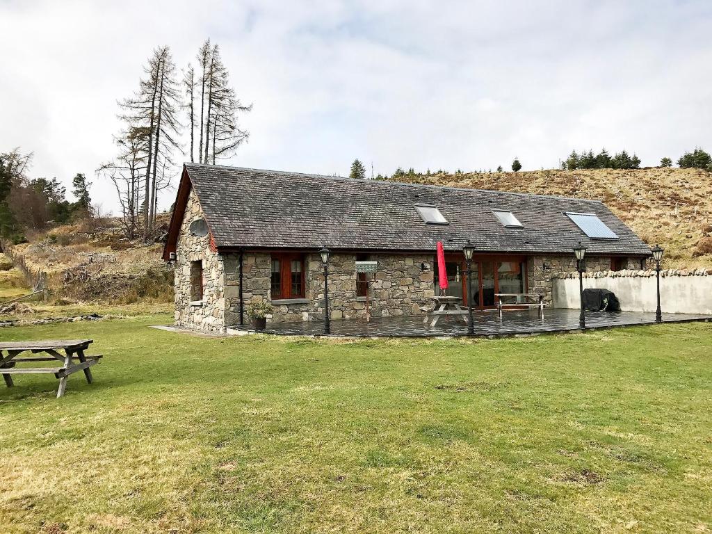 a small stone building with a picnic table in a field at Turin Nurin Cottage in Tomatin