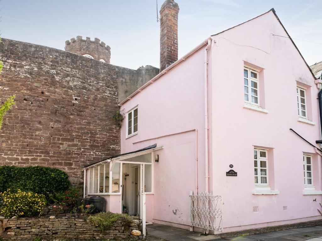 a white house in front of a brick wall at Columbine Cottage in Ross on Wye