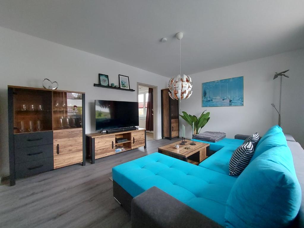 a living room with a blue couch and a tv at Ferienhaus Hinrichs 