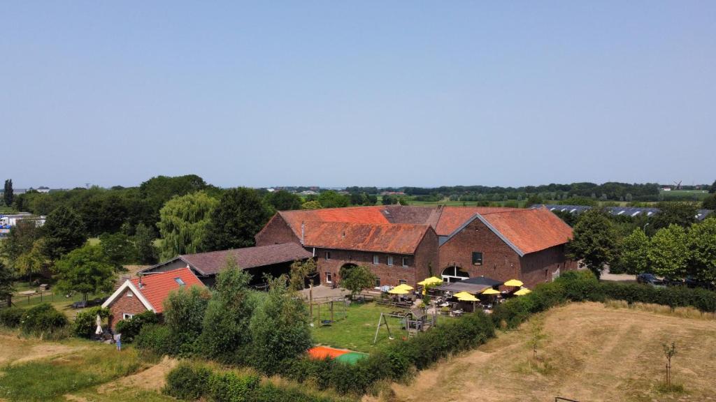 eine Luftansicht auf eine Scheune mit Tischen und Sonnenschirmen in der Unterkunft Hoeve de Binnenplaets Schimmert in Schimmert