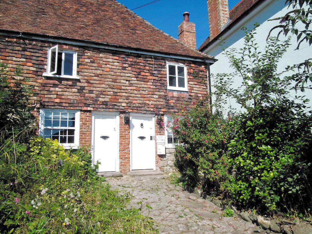 a brick house with two white doors and some bushes at Rose Cottage in Hythe