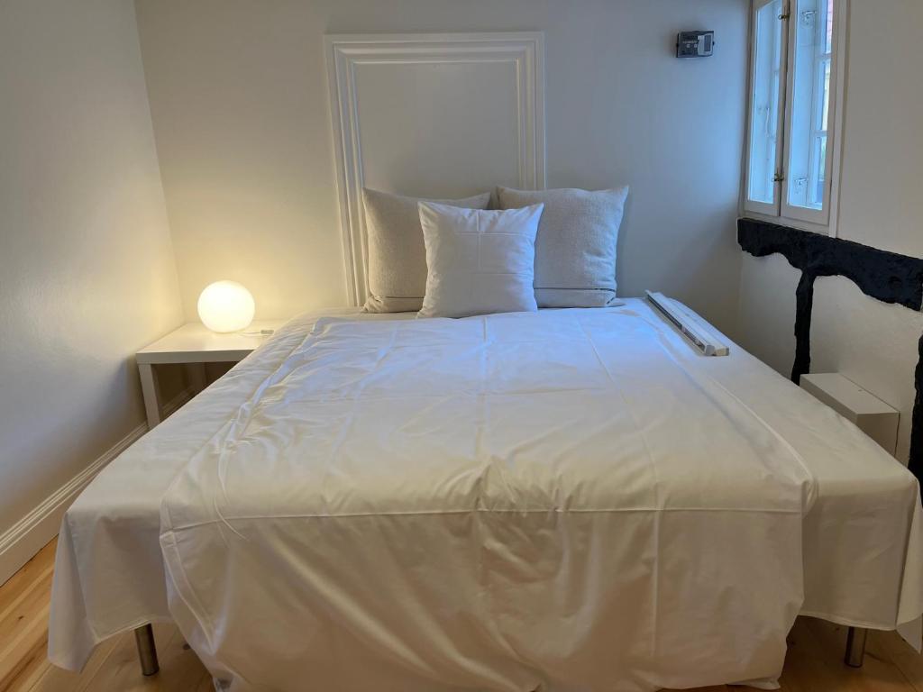 een bed met witte lakens en kussens in een kamer bij Købmandsgården in Ballen