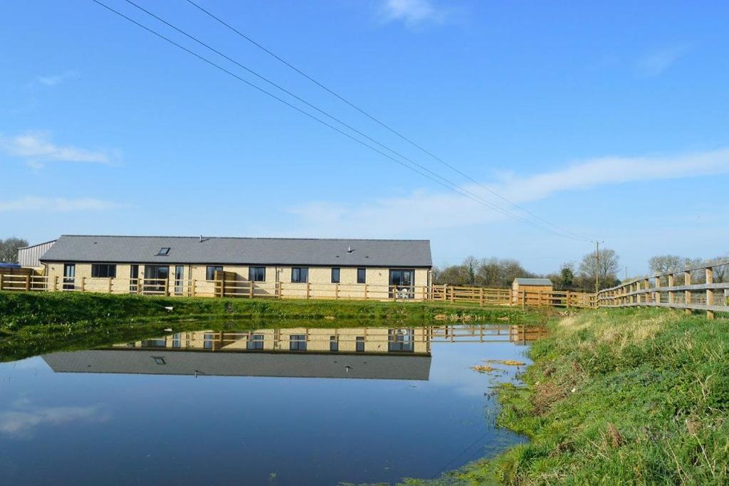 a house in a field next to a body of water at The Dairy Parlour in Cricklade