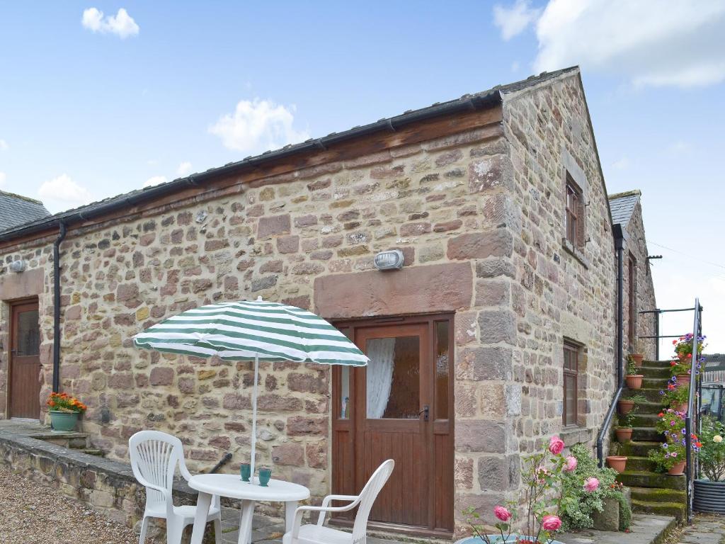 a table with an umbrella in front of a brick building at Robins Nest in Cromford