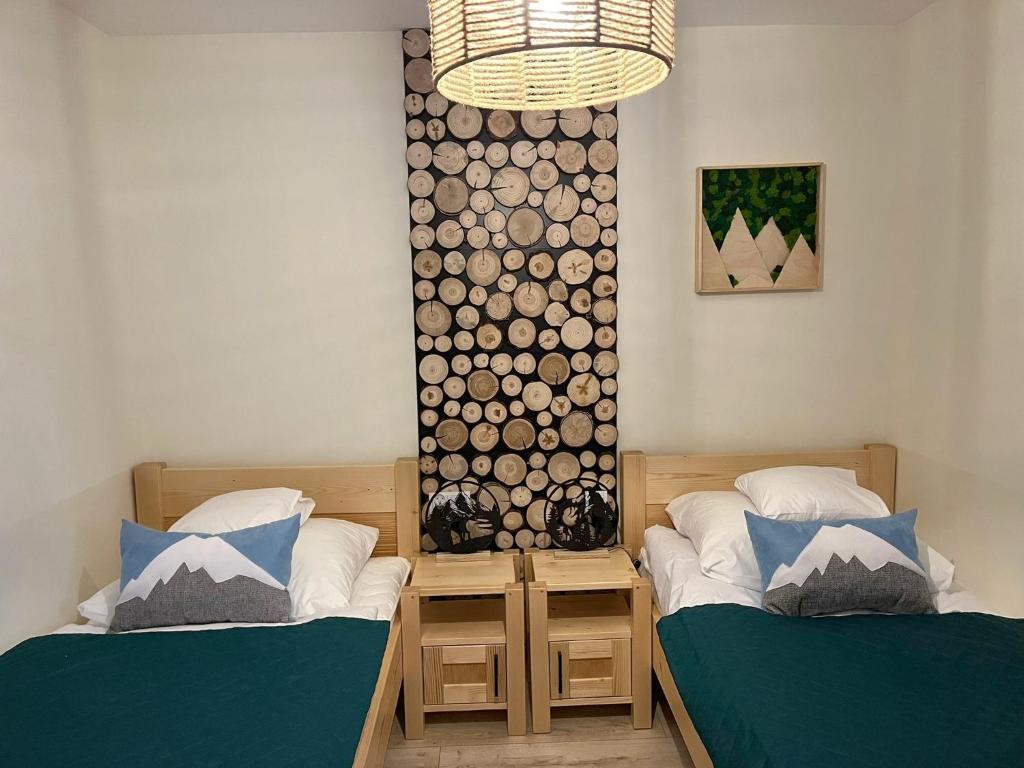 two beds in a room with a wall of logs at Moje Pieniny Apartament in Szczawnica