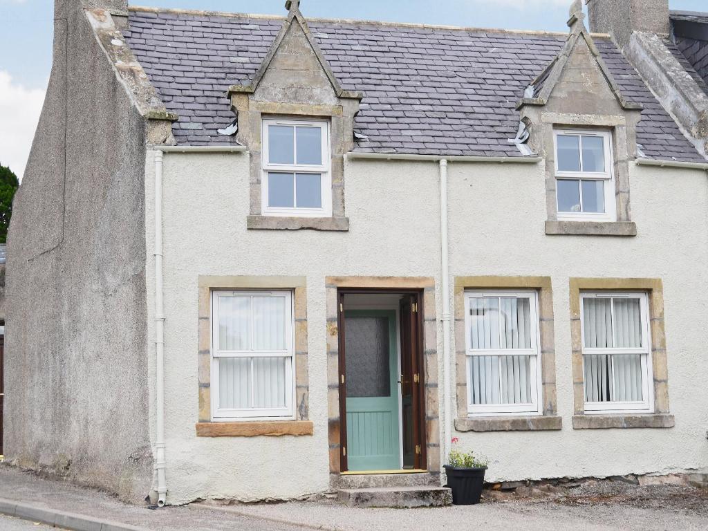 a white house with a blue door and windows at Foundry Bank in Bonar Bridge