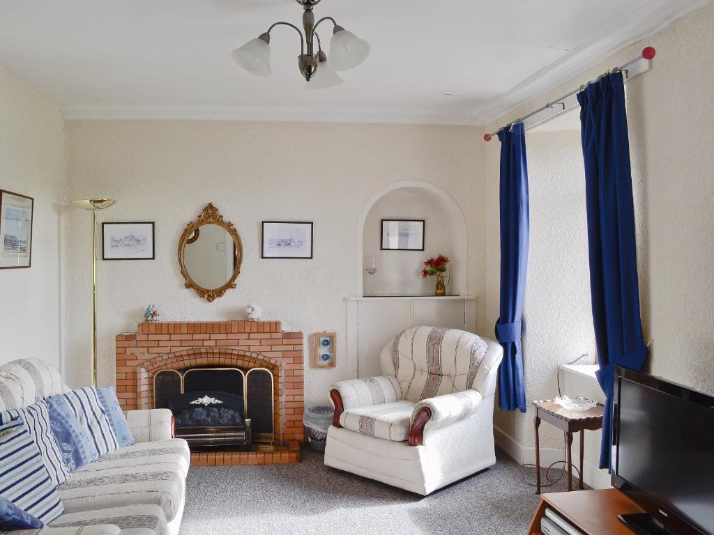 a living room with two chairs and a fireplace at Kilpatrick Farm House in Pinmore