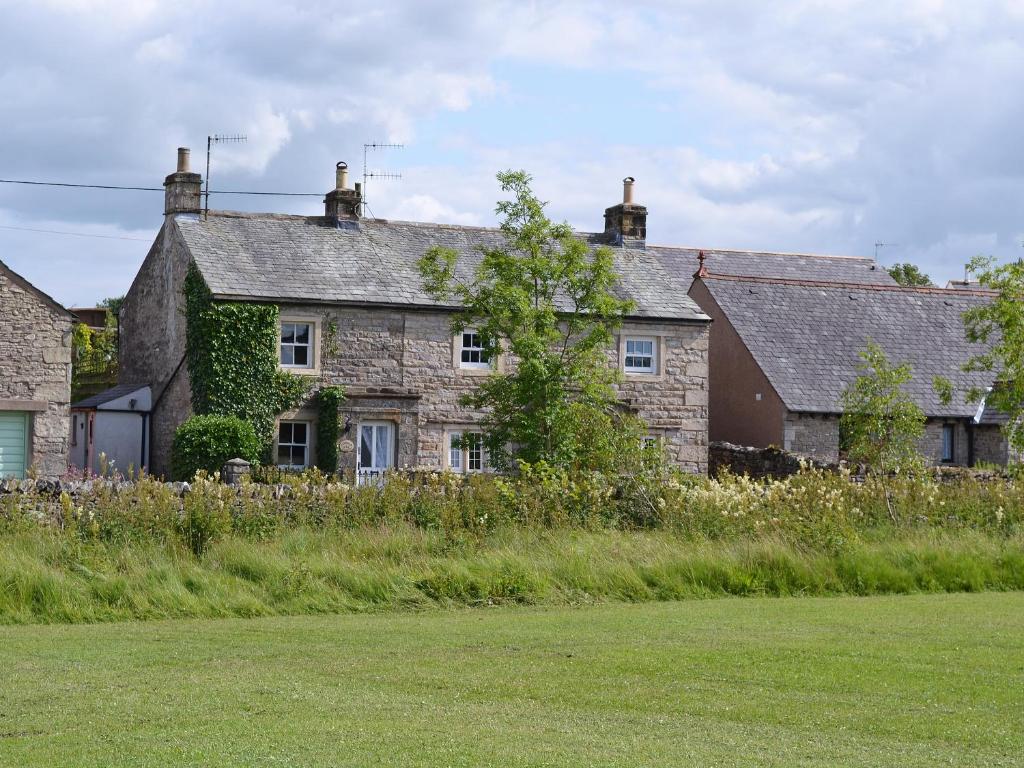 una vieja casa de piedra con hiedra creciendo en ella en Redmayne Cottage, en Orton