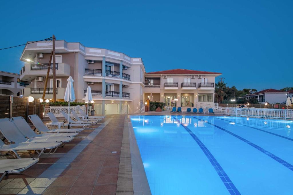 een groot zwembad met ligstoelen voor een gebouw bij Karras Hotel in Laganas