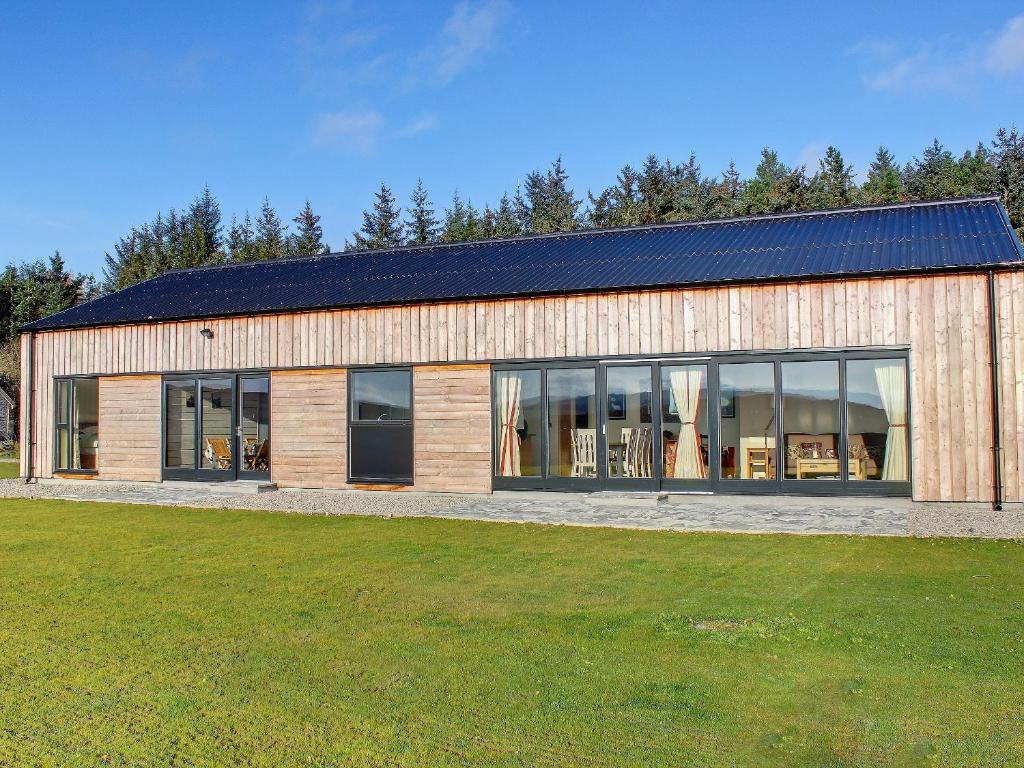 a large wooden building with a lot of windows at Phils House in Lairg