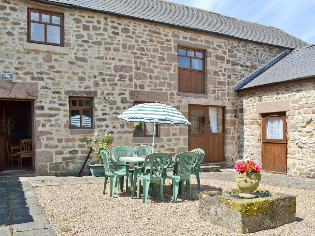 a table with chairs and an umbrella in front of a building at Swallows Loft in Cromford