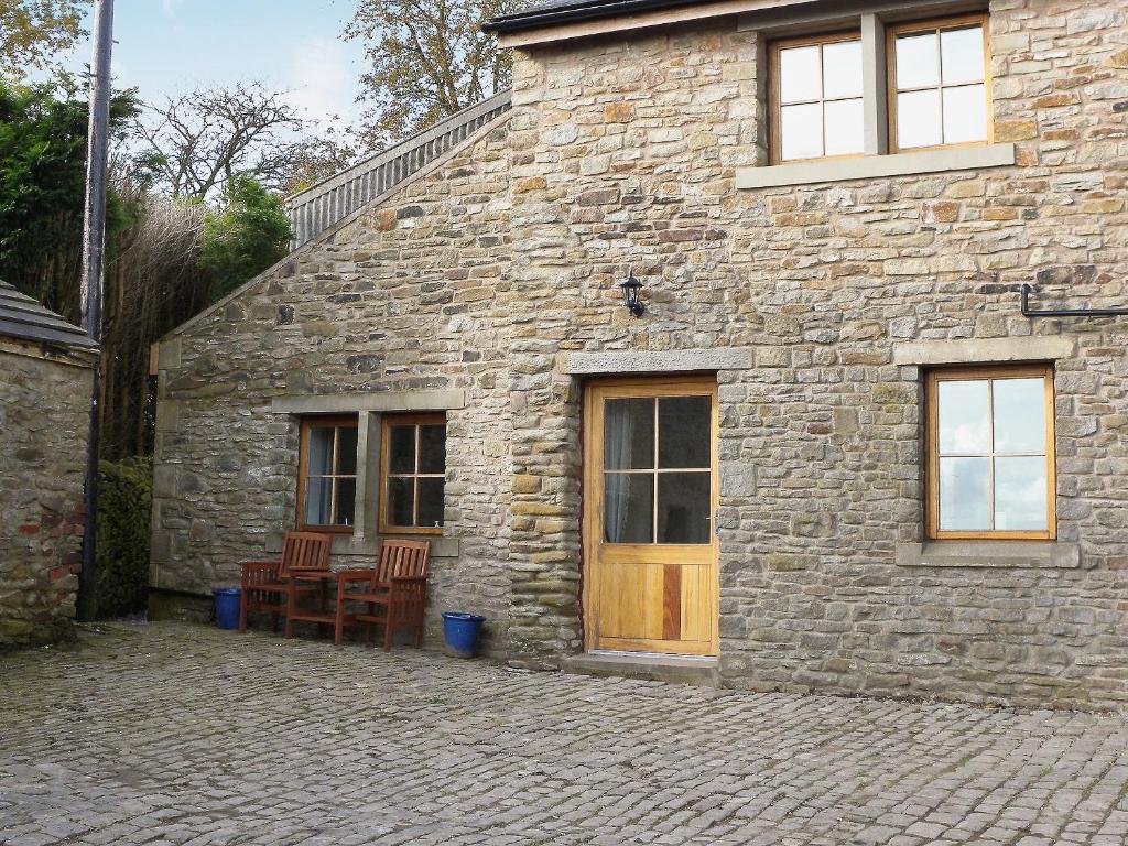 a stone building with a wooden door and two chairs at Bramble Cottage - 27978 in Whalley