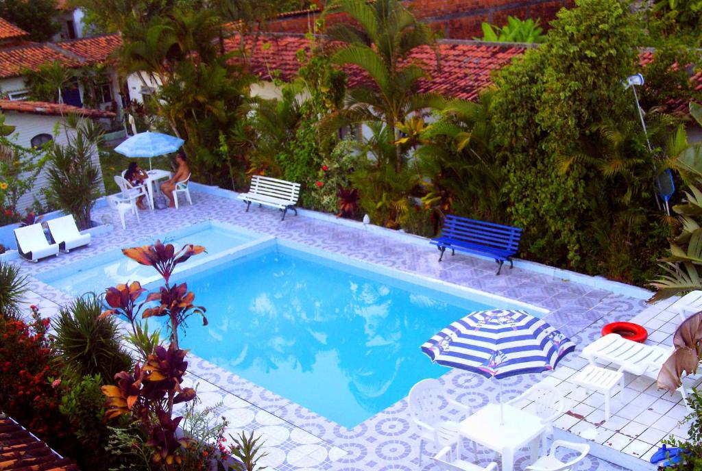 a swimming pool with two chairs and a table and benches at Pousada Ancora in Vera Cruz de Itaparica