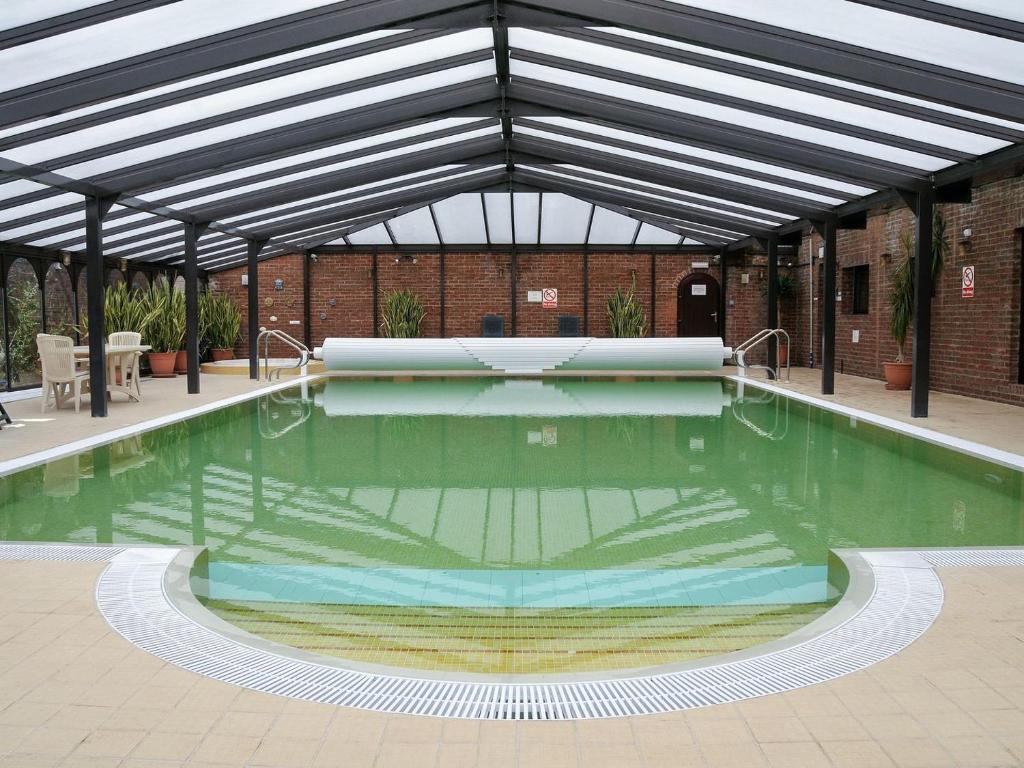 a pool in a building with awning over it at Field House in Baschurch