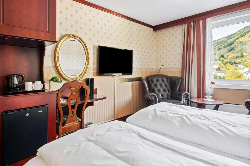 a bedroom with a bed and a mirror and a chair at Best Western Laegreid Hotell in Sogndal