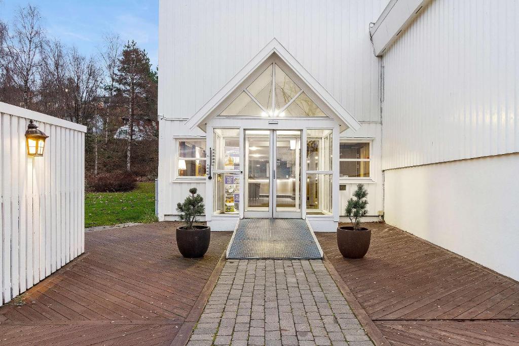 ein weißes Haus mit zwei Topfpflanzen davor in der Unterkunft Best Western Tingvold Park Hotel in Steinkjer