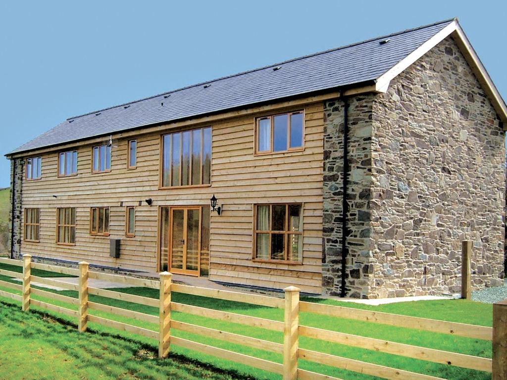 a wooden house with a fence in front of it at Cwm Corn Barn - Hw7662 in Mochdre