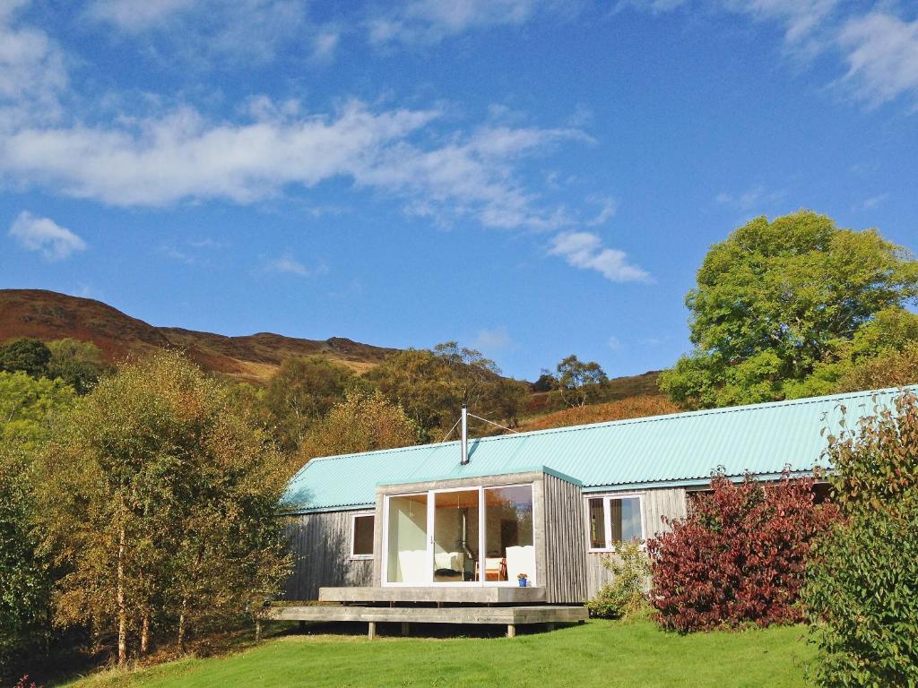 une maison avec un toit bleu et une cour herbeuse dans l'établissement West Bothy, à Glenborrodale