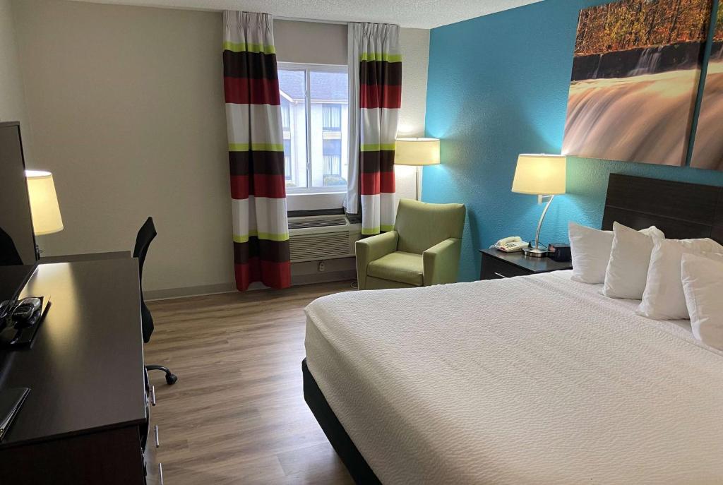 a hotel room with a bed and a desk and a chair at Days Inn by Wyndham Carthage in Carthage