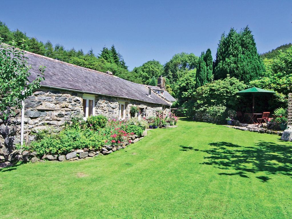 a stone building with a grass yard next to a house at Tremafon in Barmouth