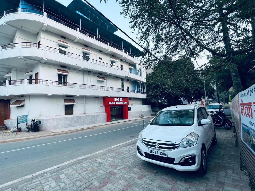 un coche blanco estacionado frente a un edificio en HOTEL RAJGIR INTERNATIONAL, en Rajgir