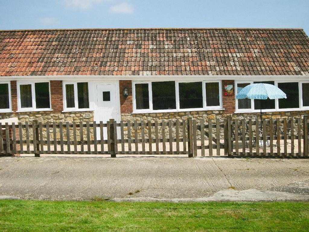 a house with a wooden fence and an umbrella at Woodpecker in Burton Bradstock