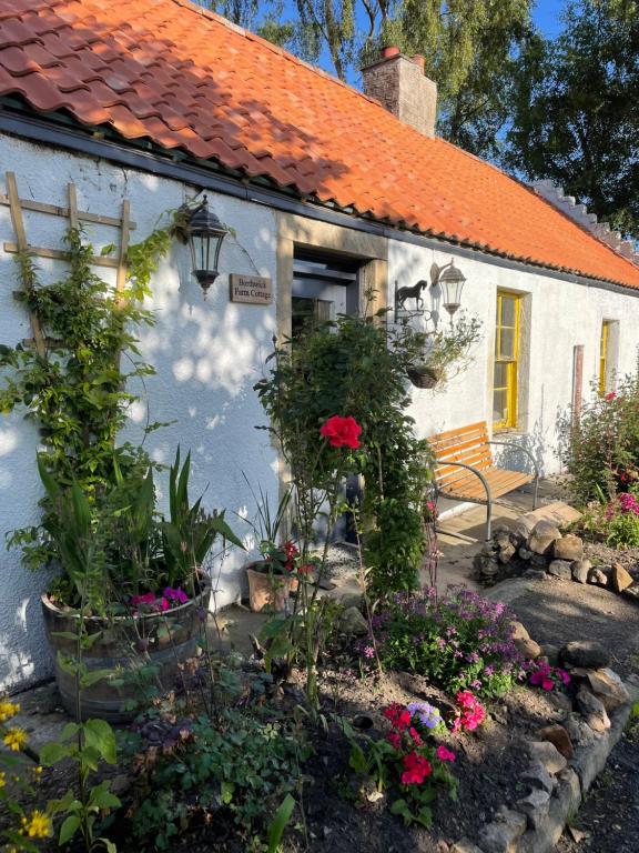 a white house with flowers in front of it at Borthwick Farm Cottage Annex in Gorebridge