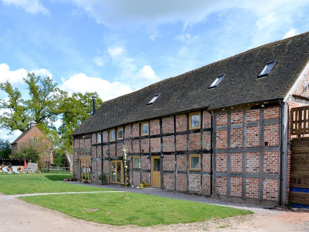 een groot bakstenen gebouw met een zwart dak bij The West Barn in Hanley Castle