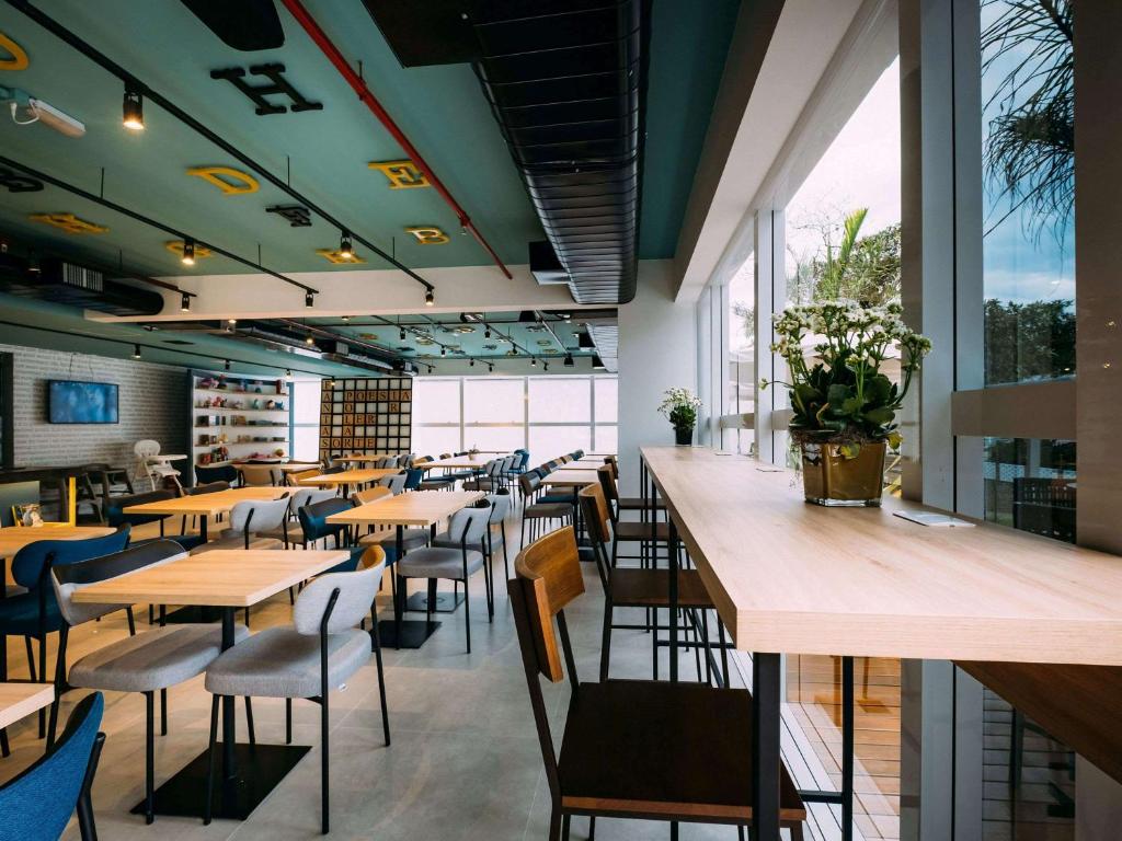 un restaurant avec des tables et des chaises en bois ainsi que des fenêtres dans l'établissement ibis Styles Poços de Caldas, à Poços de Caldas